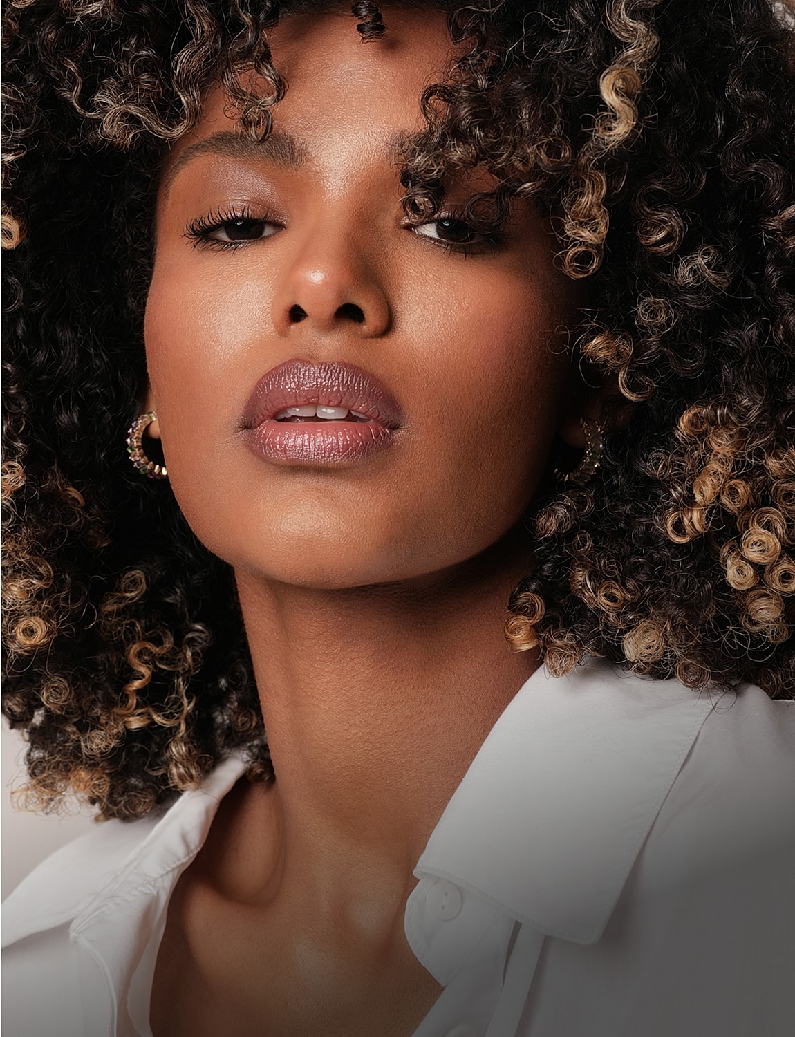 Close-up of woman with curly hair and earrings.